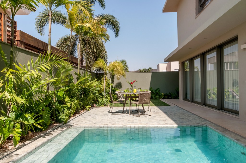 Construída do zero, casa une ambientes integrados e design nacional. Projeto de Paiva e Passarini Arquitetura. Na foto, varanda com jardim e piscina.