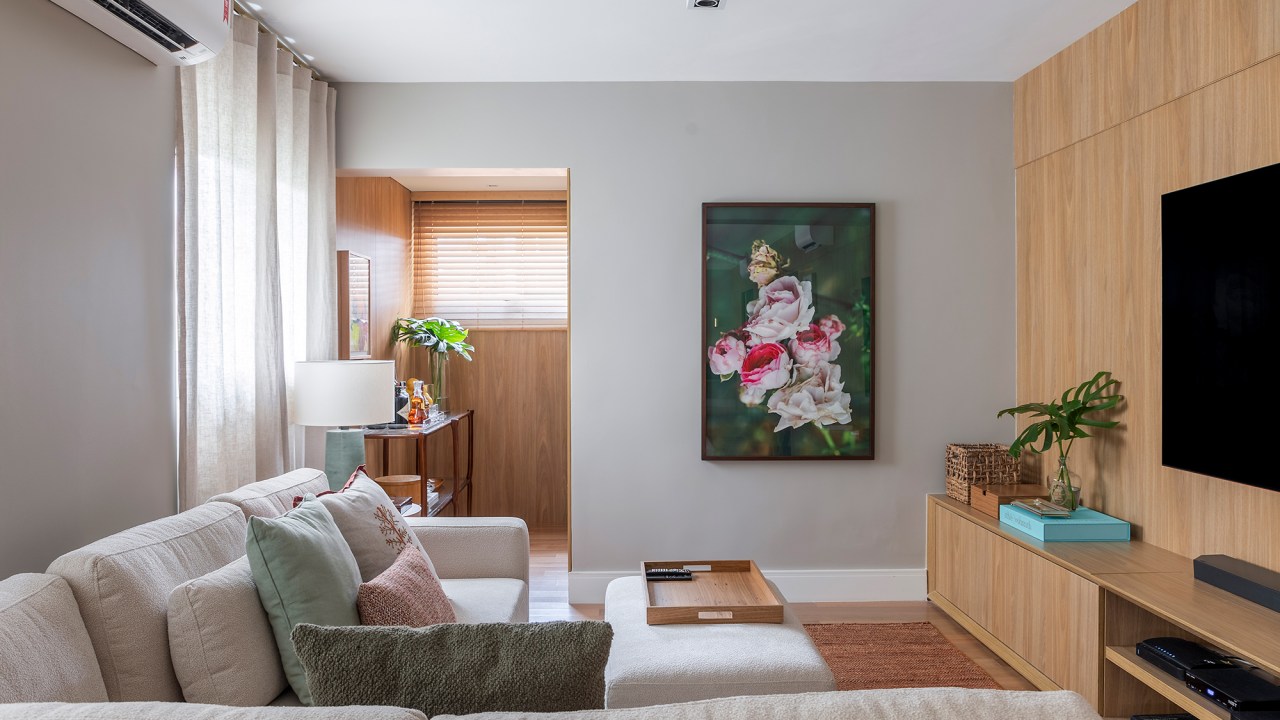 Paola Ribeiro assina apartamento de 196 m² com alma carioca em SP. Projeto de Paola Ribeiro, Na foto, sala de tv com sofá em L branco e quadro.