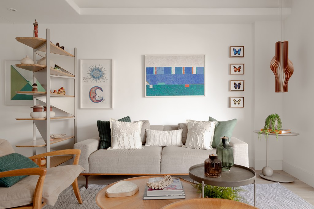 Sem quebra-quebra, apê de 150 m² aposta em tons suaves e cozinha verde. Projeto de Ana Cano. Na foto, sala de estar com sofá, quadro e luminária.