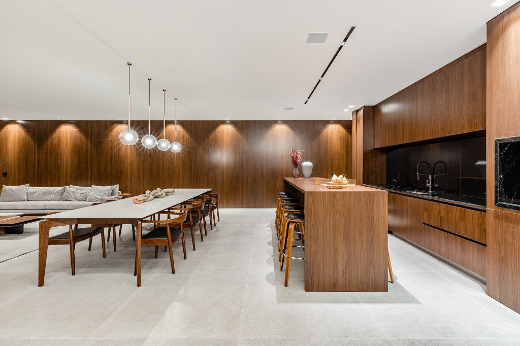 Tons escuros e grandes aberturas criam sofisticação em casa de 430 m². Projeto de Aline Borges. Na foto, sala de estar e jantar com parede de madeira.