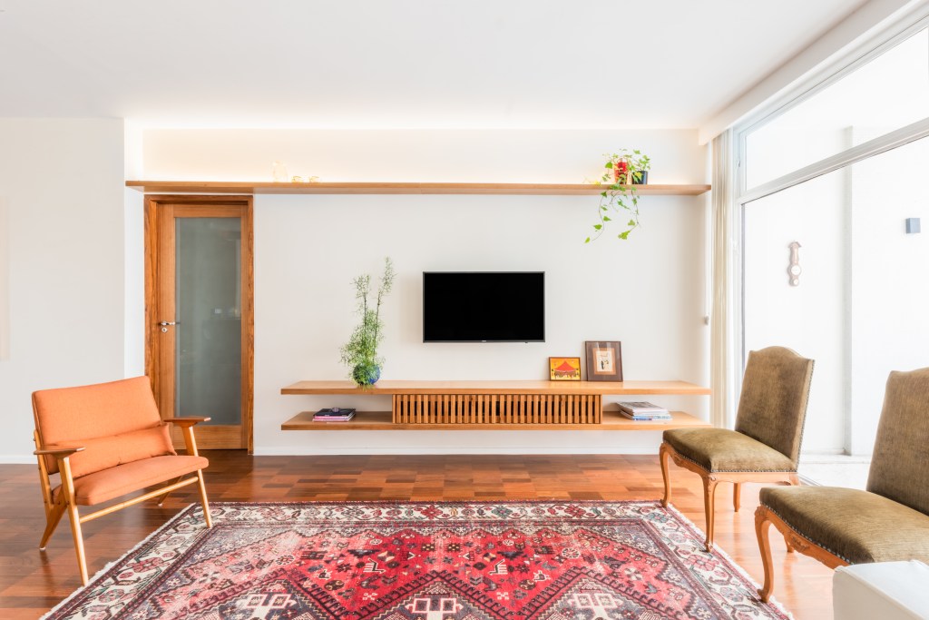 Móveis de antiquários e móveis modernos se complementam em um cenário moldado por um piso de taco restaurado e paredes claras, que amplificam a luminosidade generosa do espaço.