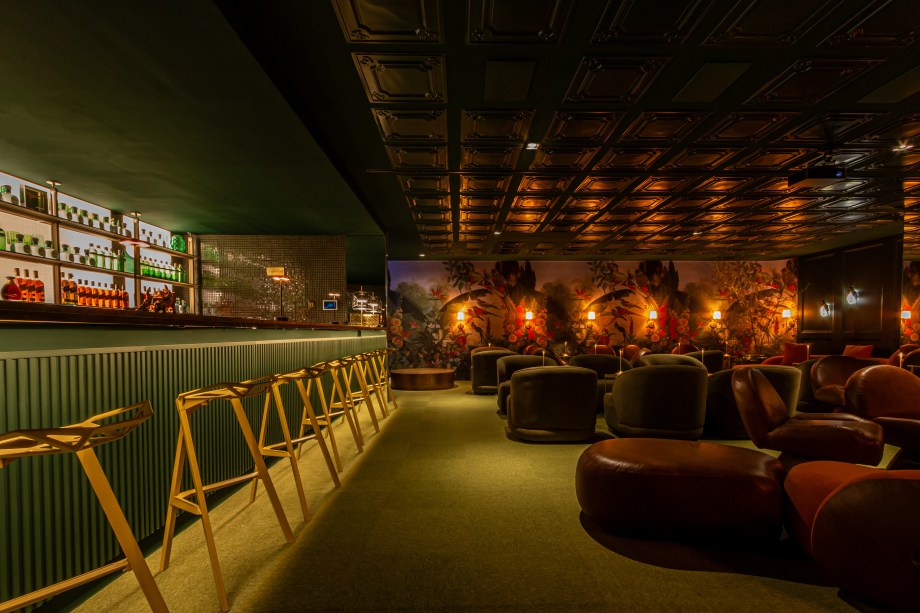 <b>Rafa Zampini Arquitetura - Bar Adorado</b>. Por trás de uma acolhedora recepção e de uma passarela envolvida por cortinas de veludo se esconde o bar secreto de 120 m², no melhor estilo speakeasy. Operado pelo Guilhotina, ele propõe uma pausa na agitação, um lugar para conversar baixo ao som de boa música em lounges privativos. O palco móvel para pequenas apresentações, as luzes que geram cenários diversos e o balcão esculpido em mármore ditam a atmosfera. Assinados pelo arquiteto, os móveis atemporais ganham a companhia de peças de couro, espelhos e das pinturas realistas do artista Lucio Carvalho.